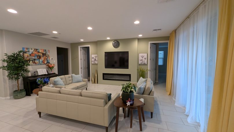 Bright, comfortable living room at Desert Willow Memory Care with fireplace, large television, comfortable seating, and natural light.