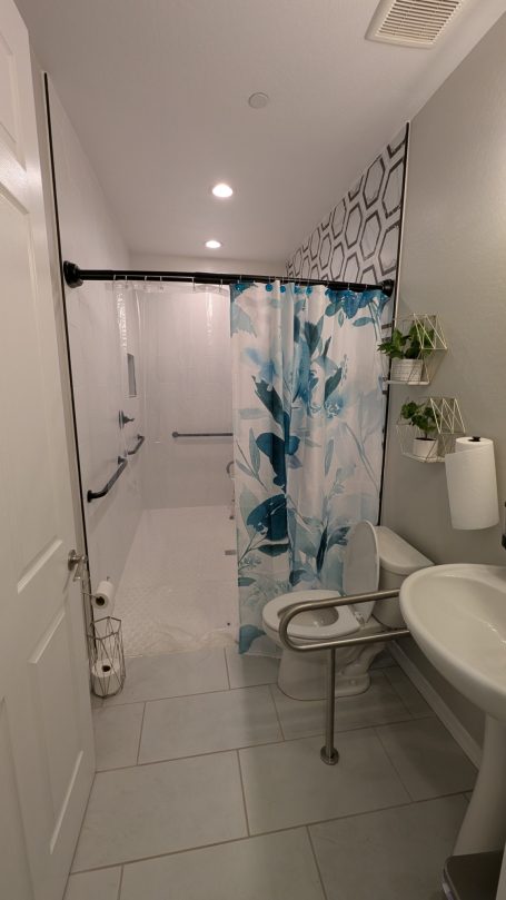 Wheelchair-accessible bathroom with roll-in shower and safety grab bars at Desert Willow Memory Care.